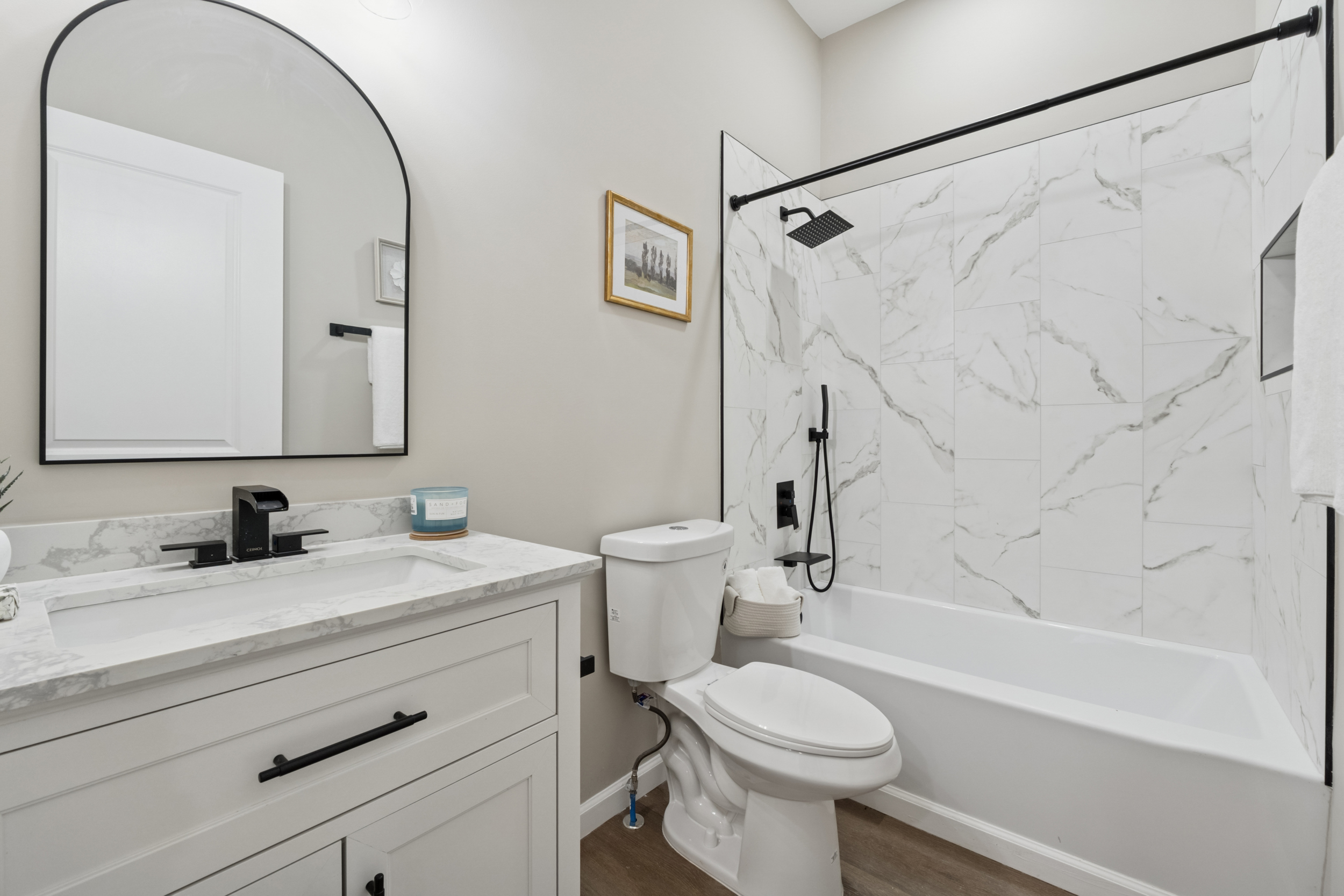 Bathroom with marble vanity, arched mirror, and tub