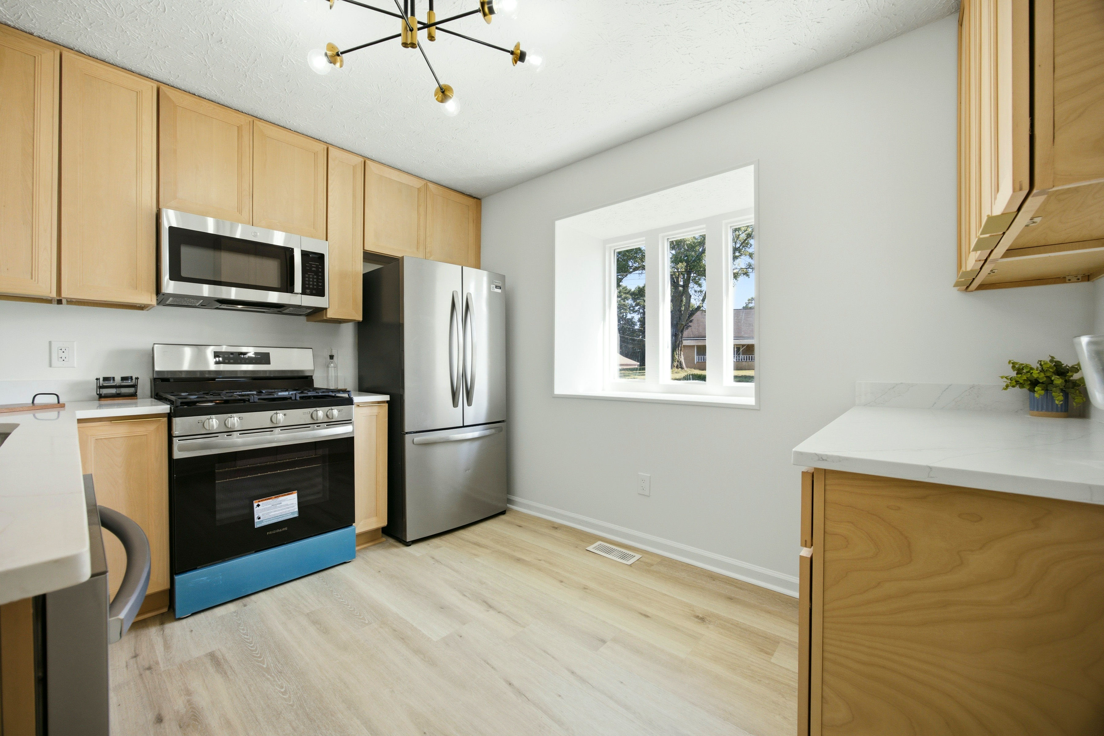 Light wood kitchen with stainless fridge and microwave