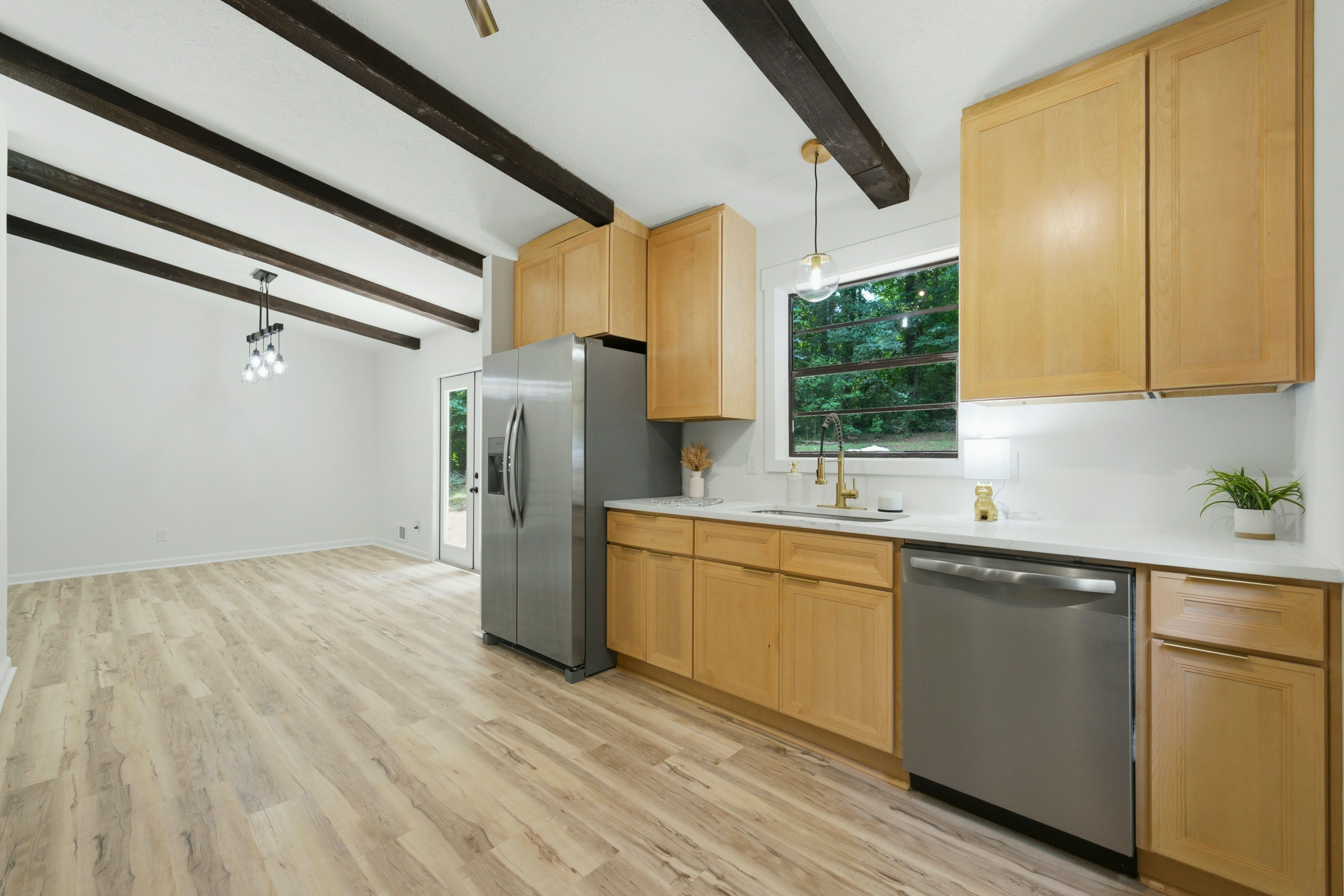 Light wood kitchen with stainless fridge and dark ceiling beams