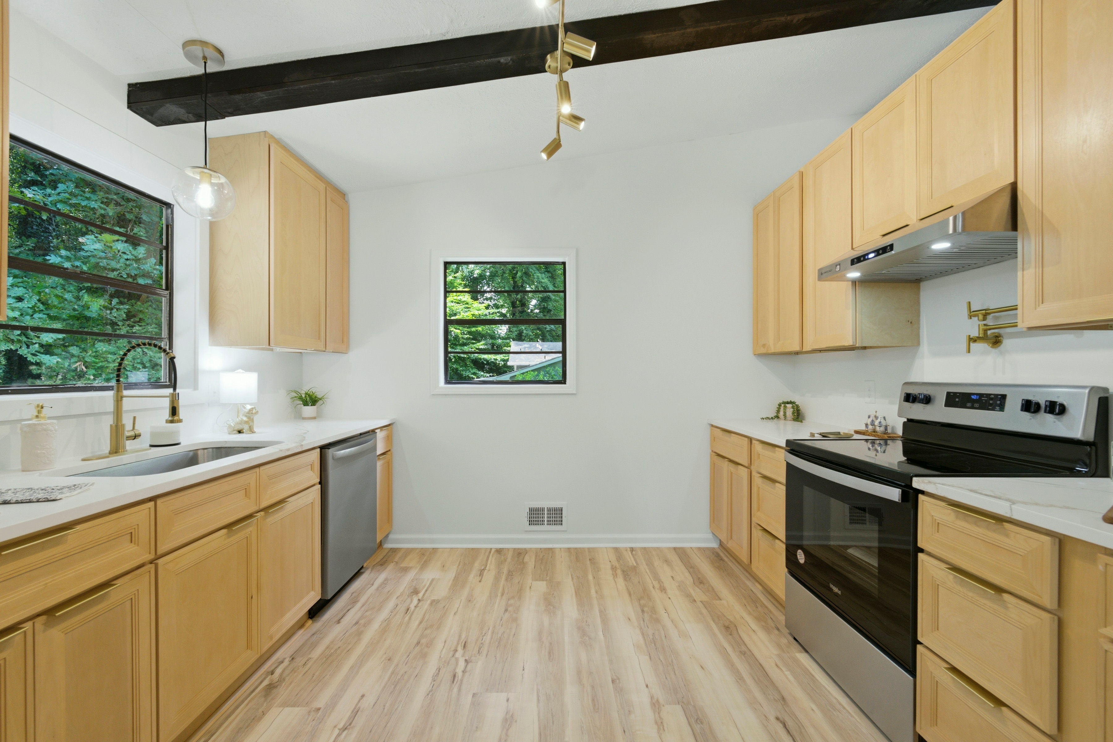 Light wood kitchen with black ceiling beam and stainless range