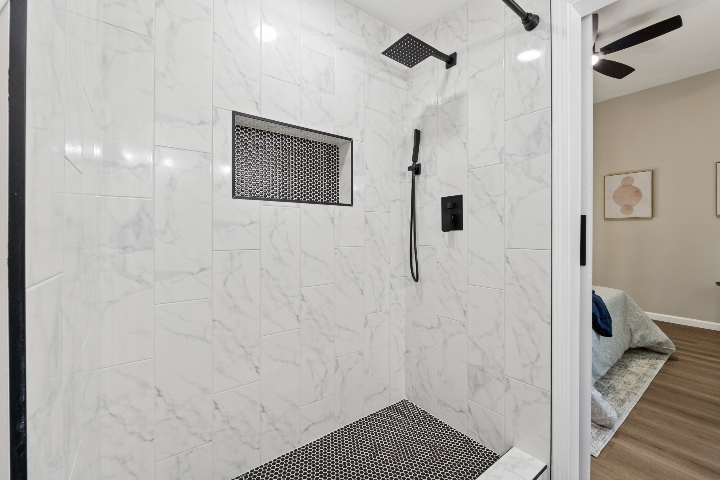 Walk-in shower with marble tile and black fixtures